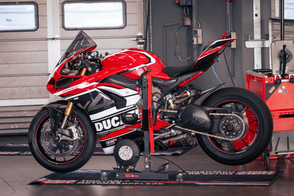 Ducati sports Bikes A vibrant red Ducati Panigale motorcycle in a Nürburgring garage setting.