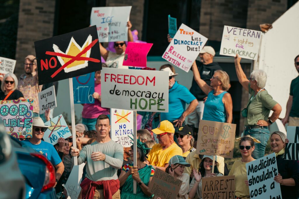 A diverse group of protesters holds signs advocating for freedom and democracy at a daytime rally.