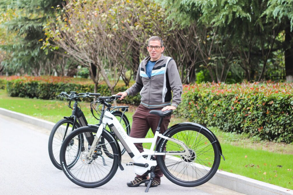 Man with two electric bicycles enjoying a day outdoors in a park setting.