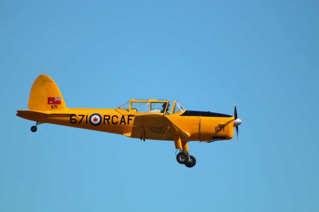 A vibrant yellow RCAF airplane flying against a clear blue sky, showcasing vintage aviation.