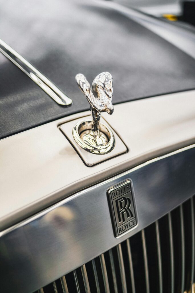 Detailed close-up of the iconic Rolls-Royce emblem and grille on a luxury car hood, showcasing elegance.