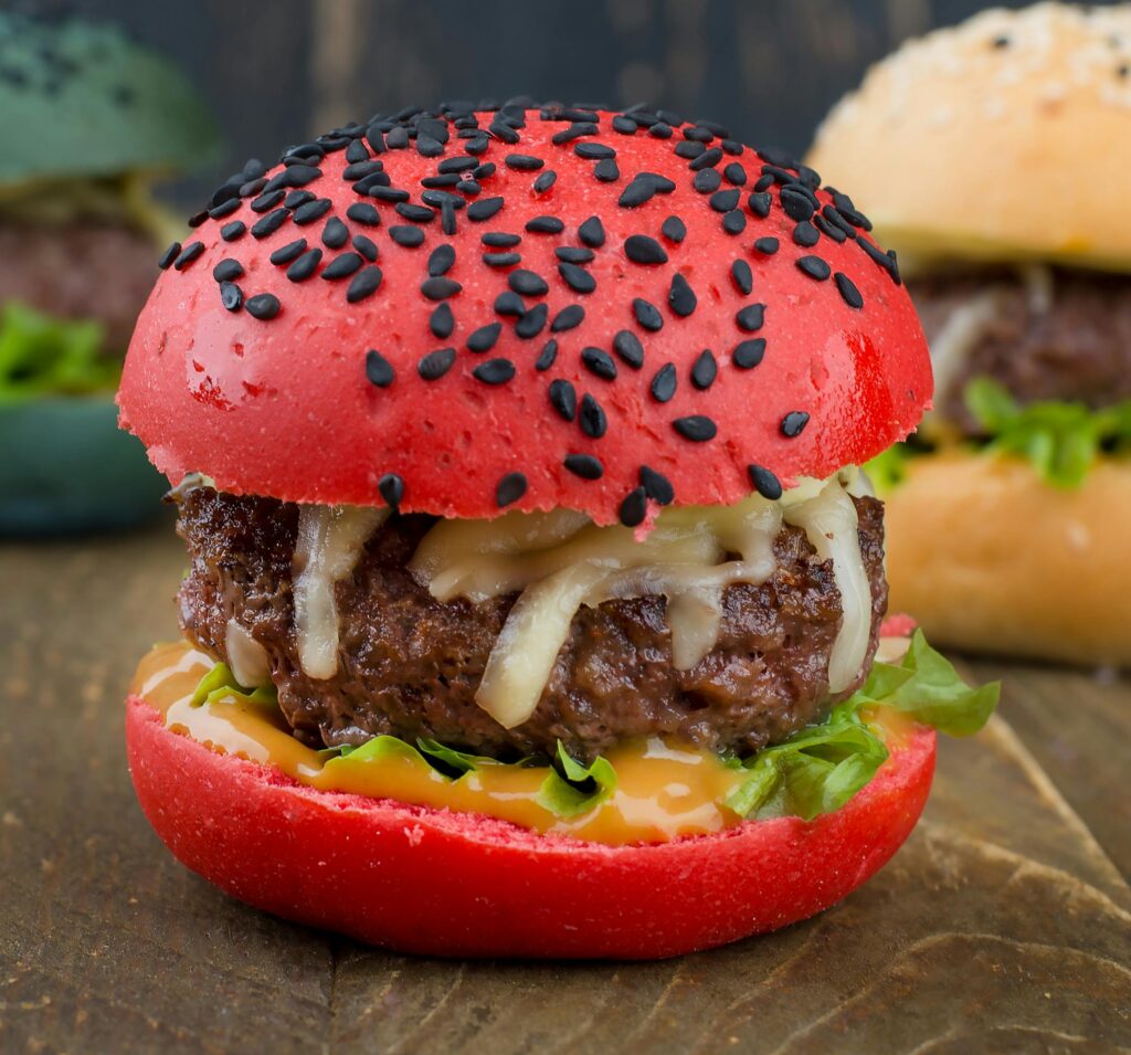 Close-up of a delicious gourmet burger with a red bun, cheese, and fresh lettuce.