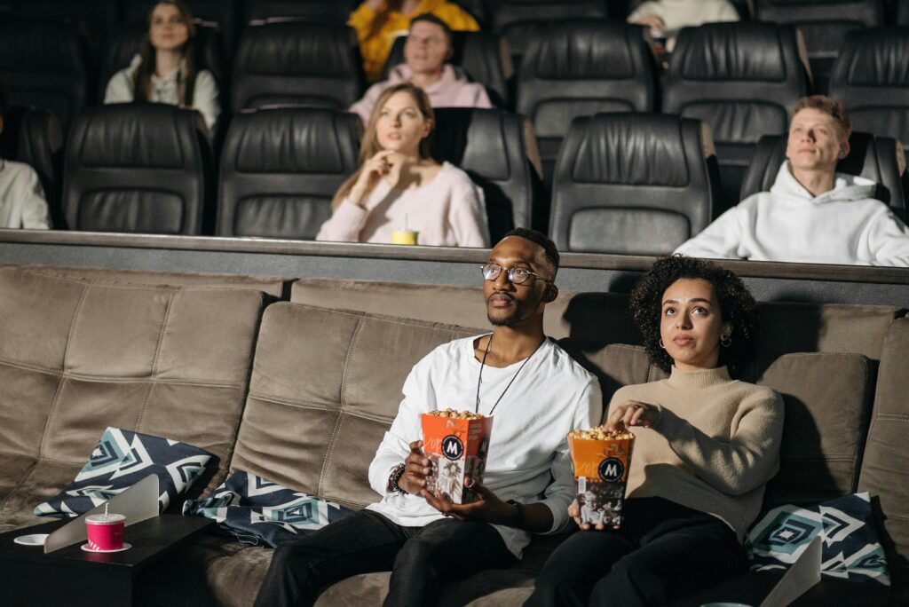 Inside Out 2,Topper Movie A couple enjoys popcorn while watching a movie in a cozy cinema environment, surrounded by others.