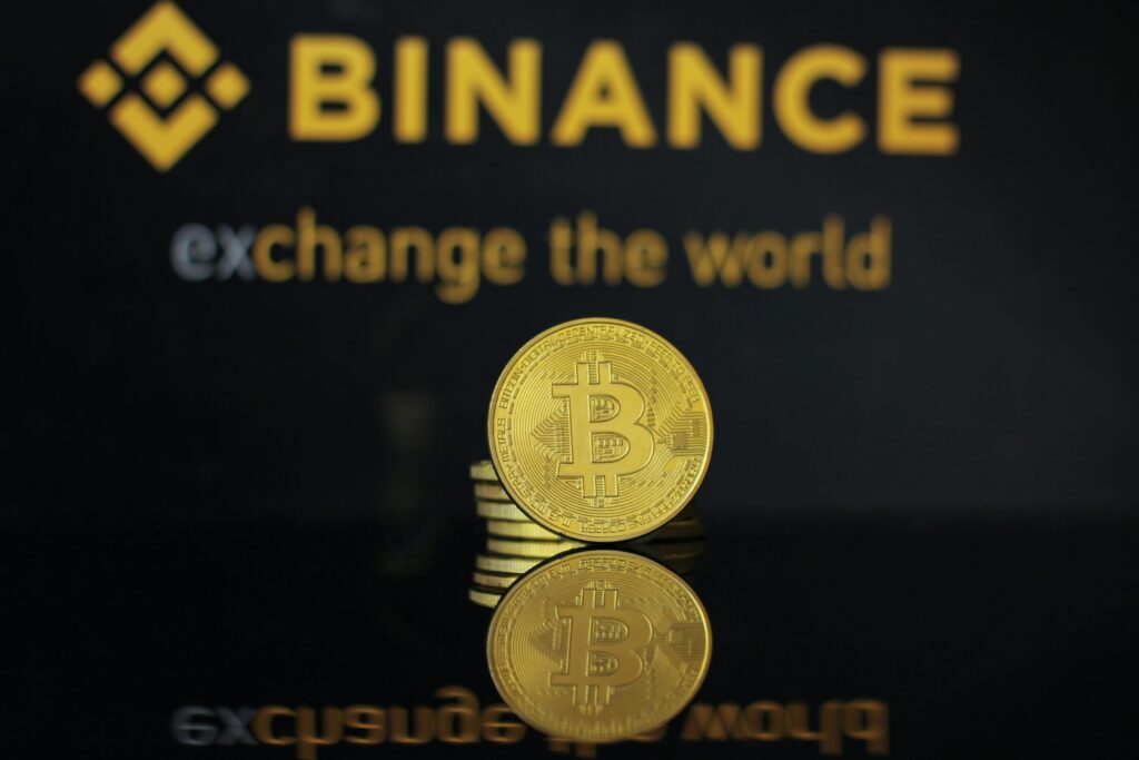 XRP Price in the USA Close-up of a Bitcoin coin with Binance logo and text reflecting in dark surface.