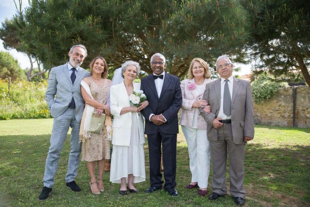 Senior couples joyfully celebrating a wedding in a beautiful outdoor garden setting.