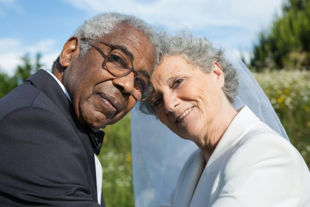 Senior couple in wedding attire, embracing happily outdoors in Portugal.